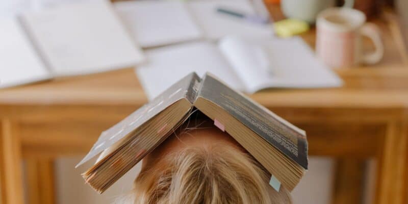 Naine istub ja tal on avatud raamat peas, stress