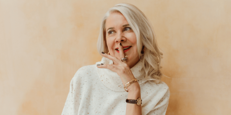 Kollageen, keskealine naine, sõrm huultel ja naeratab