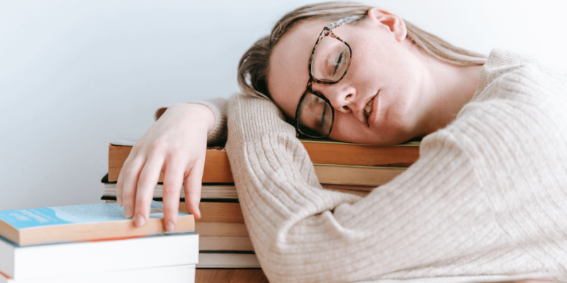 Naine magab, pea raamatute hunniku otsas